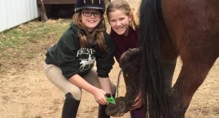 girls cleaning a horse shoe