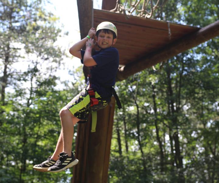 Boy being lowered off of ropes course